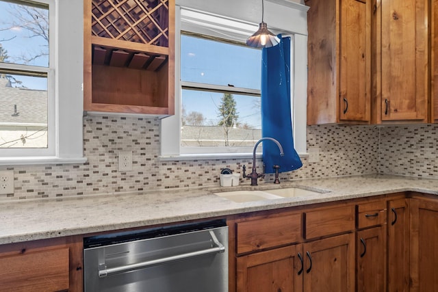 kitchen featuring dishwasher, brown cabinetry, decorative backsplash, and a sink