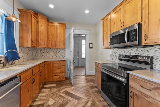 kitchen with a sink, tasteful backsplash, recessed lighting, light stone countertops, and appliances with stainless steel finishes