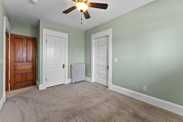unfurnished bedroom featuring baseboards, carpet flooring, ceiling fan, and radiator