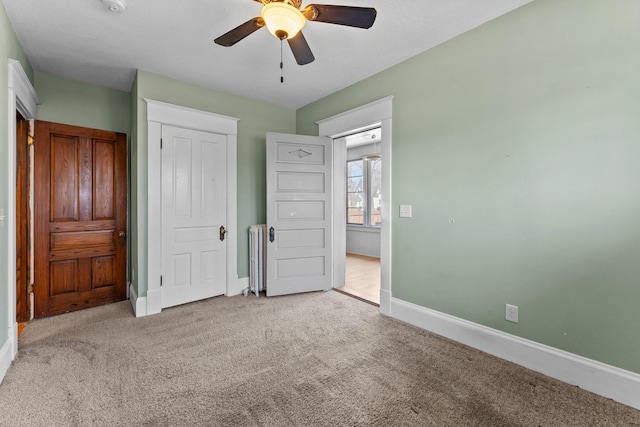 unfurnished bedroom with radiator, baseboards, a ceiling fan, and carpet