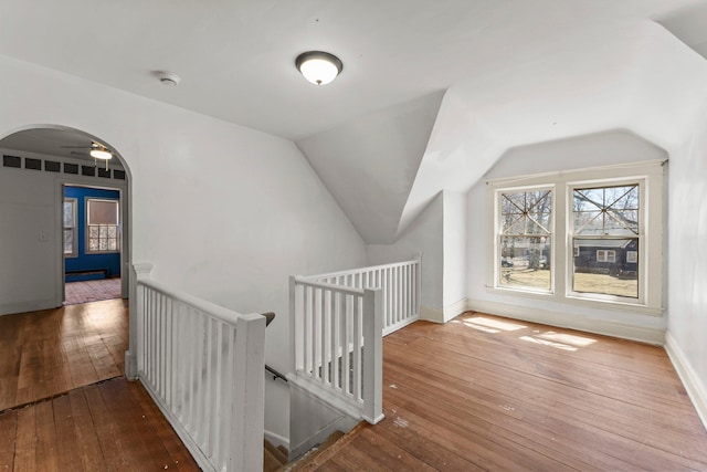 bonus room featuring a baseboard heating unit, arched walkways, baseboards, lofted ceiling, and hardwood / wood-style flooring