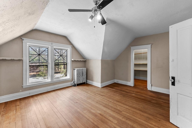 bonus room with radiator, vaulted ceiling, baseboards, and hardwood / wood-style flooring