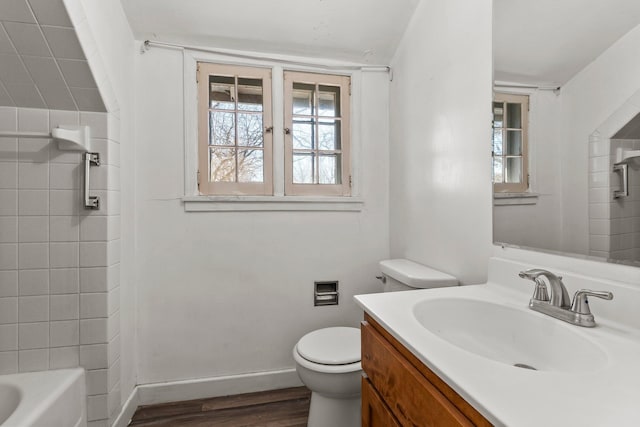 bathroom featuring toilet, vanity, wood finished floors, and a wealth of natural light