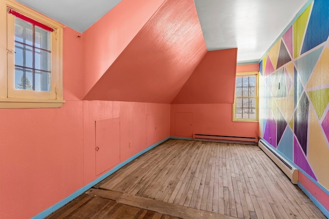 additional living space with lofted ceiling, baseboard heating, baseboards, a baseboard radiator, and hardwood / wood-style flooring