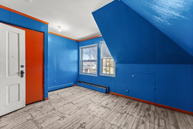 additional living space with baseboards, wood finished floors, lofted ceiling, and baseboard heating