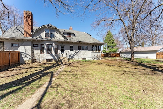 back of property featuring a chimney, fence, a yard, and stucco siding