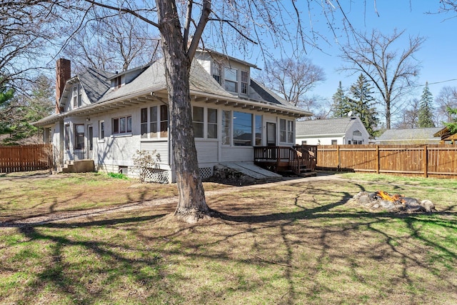 rear view of house with a chimney, fence, a shingled roof, a deck, and a yard
