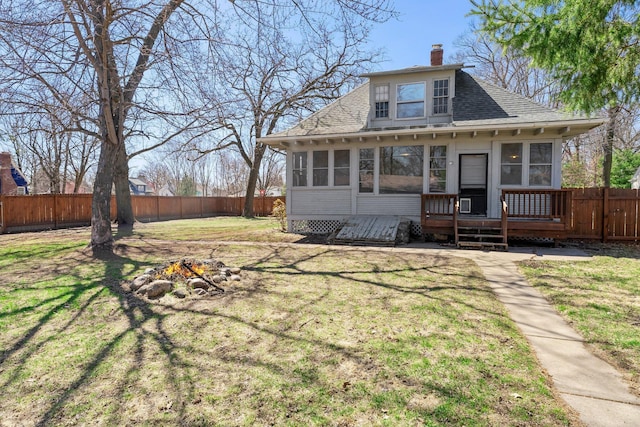 back of house featuring a fire pit, a sunroom, a shingled roof, and a fenced backyard
