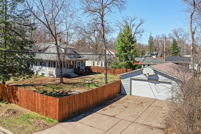 exterior space featuring driveway, fence private yard, an outdoor structure, a garage, and roof with shingles
