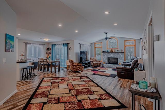 20371 Golf Crest Dr, Grand Rapids, MN 55744 - living area with a stone fireplace, a ceiling fan, lofted ceiling, wood finished floors, and baseboards