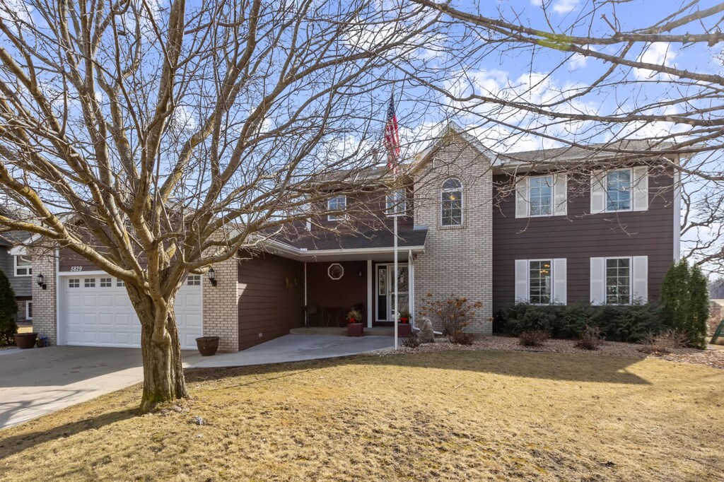 view of front facade featuring a front lawn, brick siding, and concrete driveway