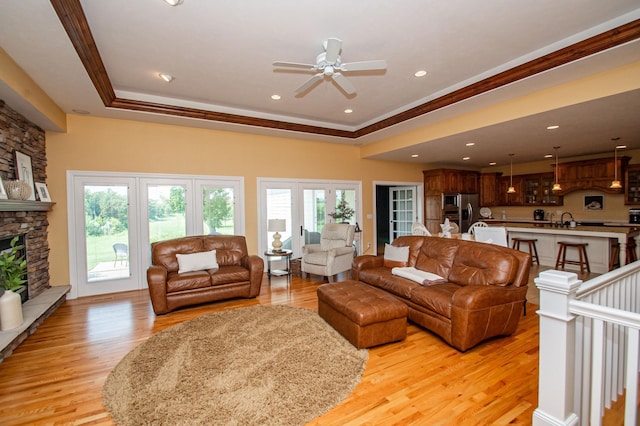 241 Cottonwood Cv, Lynd, MN 56157 - living area with a tray ceiling, a fireplace, a ceiling fan, and light wood finished floors
