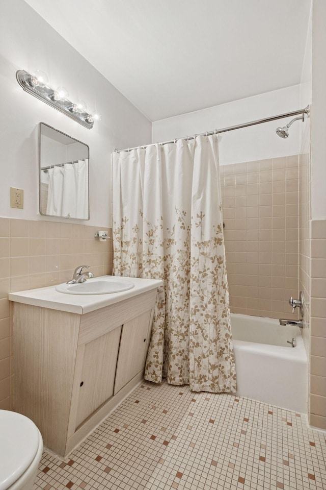 full bath with tile walls, shower / bathtub combination with curtain, vanity, and toilet