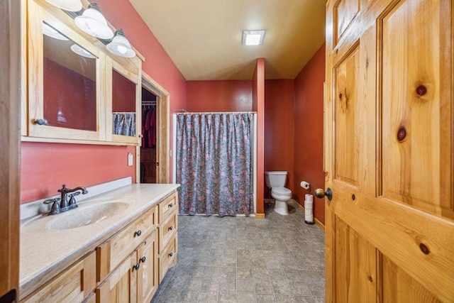 bathroom featuring a shower with shower curtain, vanity, baseboards, toilet, and stone finish floor