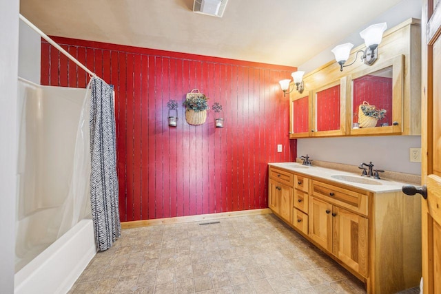 full bath featuring double vanity, wooden walls, visible vents, and a sink