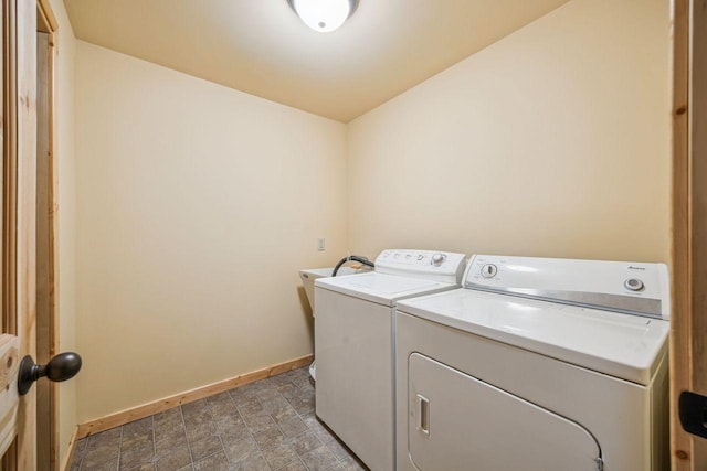 clothes washing area featuring washer and clothes dryer, laundry area, and baseboards