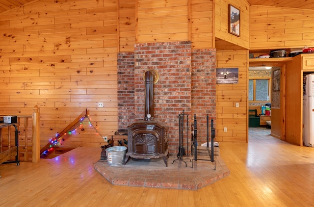 34130 Deer Lake Rd, Grand Rapids, MN 55744 - unfurnished living room with wood walls, hardwood / wood-style floors, a wood stove, vaulted ceiling, and water heater