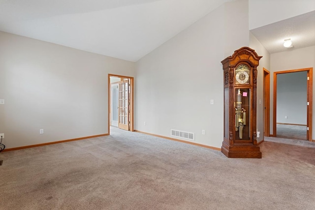carpeted empty room featuring baseboards and lofted ceiling