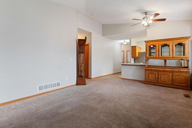 unfurnished living room featuring vaulted ceiling, light carpet, ceiling fan, and baseboards