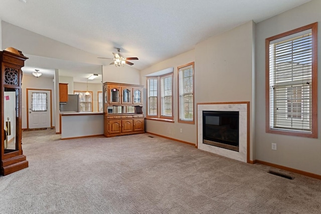 unfurnished living room with baseboards, light carpet, ceiling fan, a premium fireplace, and vaulted ceiling