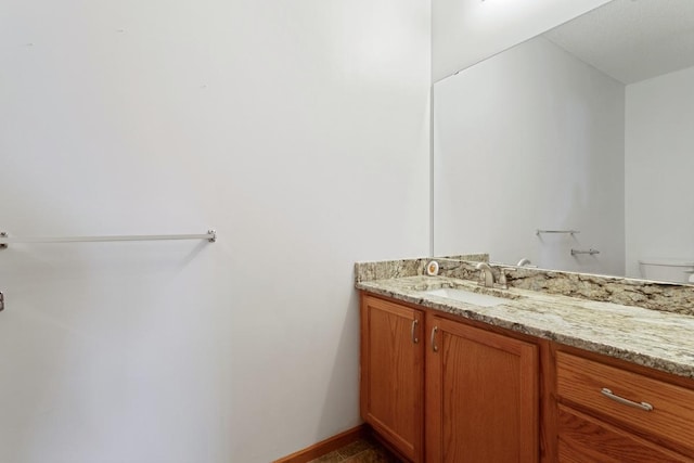 bathroom with vanity, toilet, and baseboards