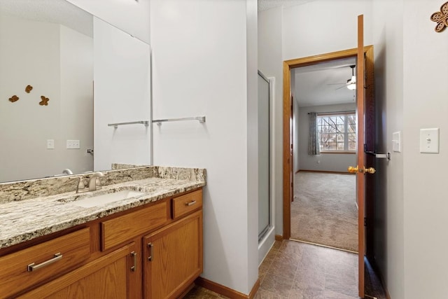 bathroom with vanity, baseboards, a shower stall, and a ceiling fan