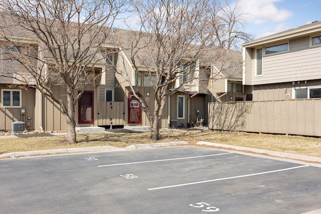 exterior space featuring central AC, fence, a residential view, and uncovered parking