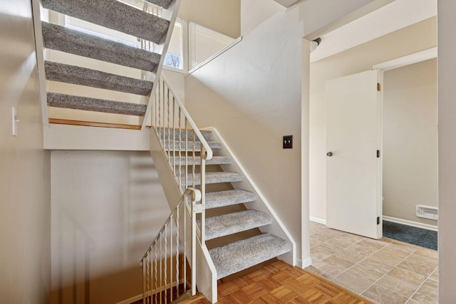 staircase featuring baseboards and visible vents