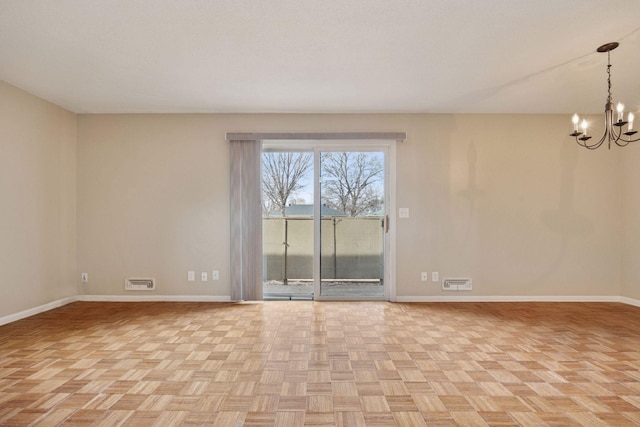 spare room featuring baseboards, visible vents, and a notable chandelier