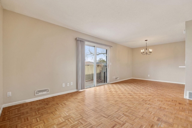 spare room with visible vents, baseboards, and an inviting chandelier