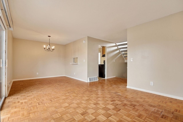 spare room featuring baseboards, a notable chandelier, and visible vents