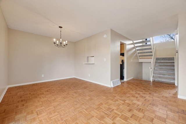 unfurnished room featuring visible vents, baseboards, and a chandelier