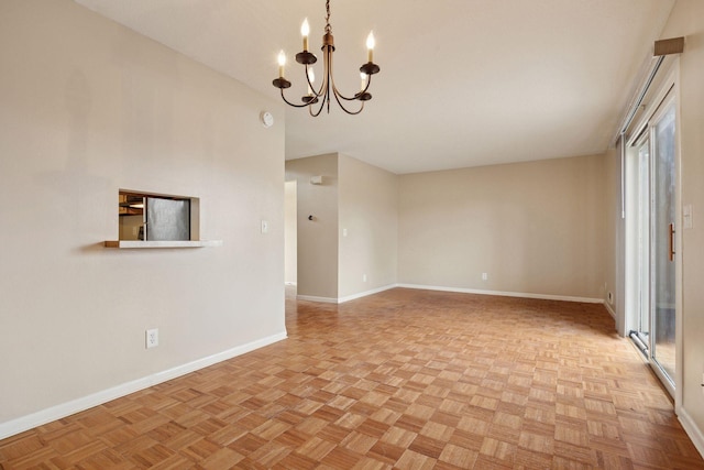 empty room featuring baseboards and an inviting chandelier