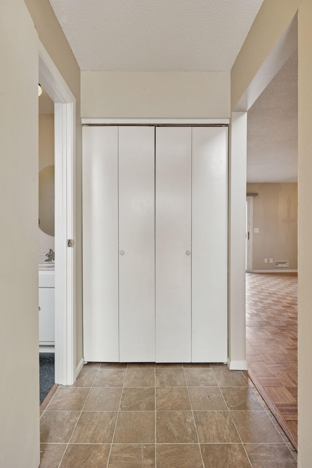 corridor featuring baseboards and a textured ceiling