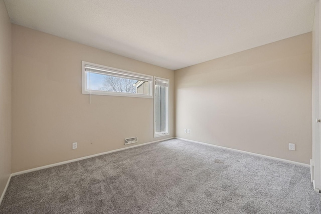 carpeted spare room featuring visible vents and baseboards