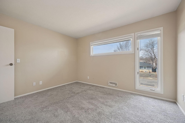 unfurnished room with carpet flooring, visible vents, and baseboards