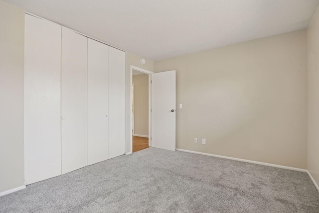 unfurnished bedroom with a closet, baseboards, and carpet floors