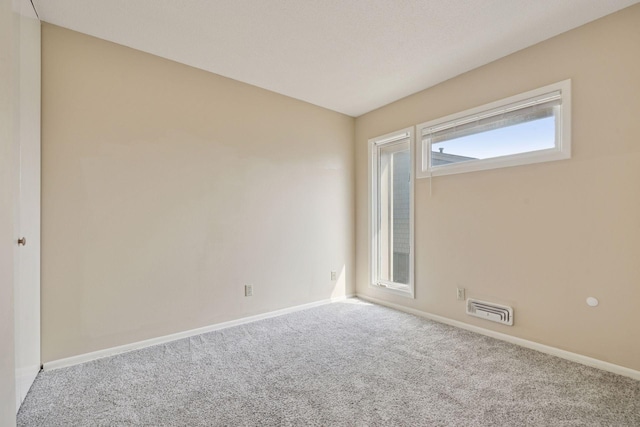 carpeted empty room featuring baseboards and visible vents