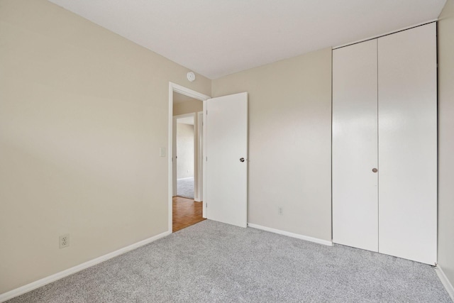 unfurnished bedroom featuring a closet, carpet flooring, and baseboards