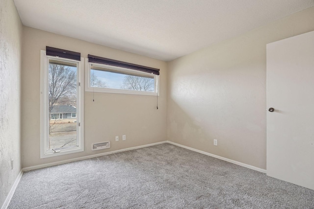 empty room with carpet, visible vents, baseboards, and a textured ceiling