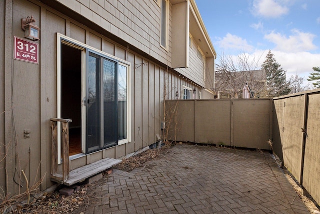 view of side of property with board and batten siding, a patio area, and a fenced backyard