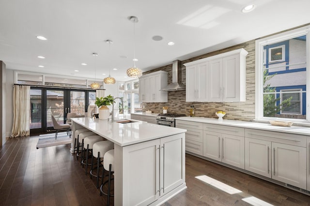 5231 Washburn Ave S, Minneapolis, MN 55410 - kitchen with a sink, wall chimney exhaust hood, a kitchen breakfast bar, light countertops, and tasteful backsplash
