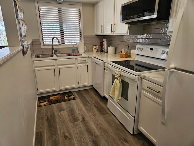 kitchen featuring white cabinets, light countertops, white appliances, dark wood-type flooring, and a sink