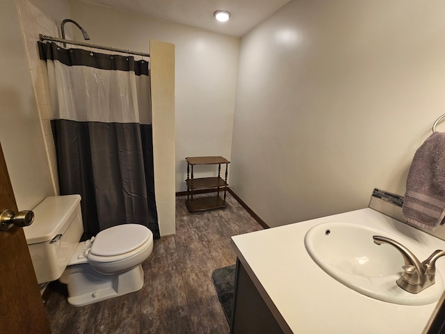 bathroom with toilet, curtained shower, vanity, wood finished floors, and baseboards