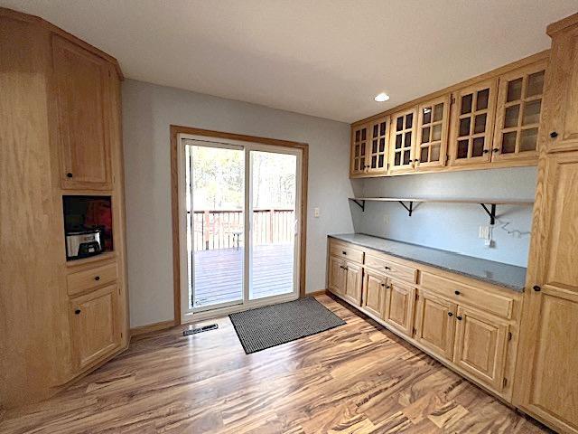 kitchen featuring recessed lighting, glass insert cabinets, light wood-type flooring, visible vents, and baseboards