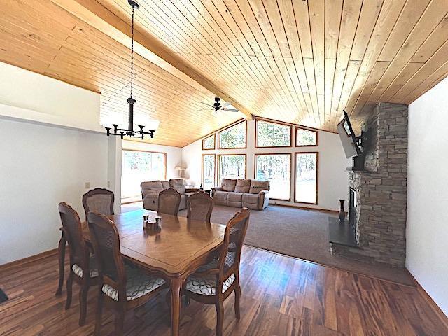 dining area with baseboards, wood finished floors, vaulted ceiling with beams, and wood ceiling