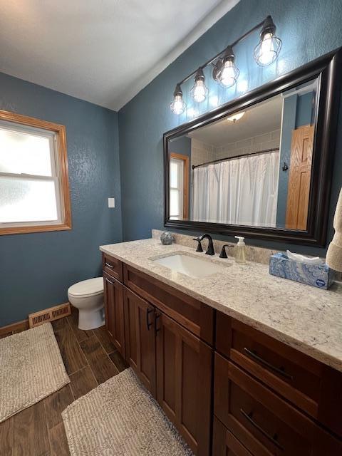 bathroom with vanity, wood tiled floor, toilet, visible vents, and baseboards