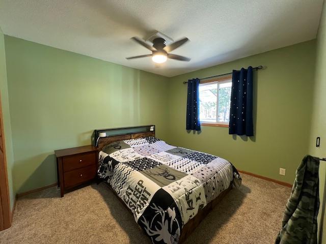 bedroom featuring baseboards, a ceiling fan, and light colored carpet