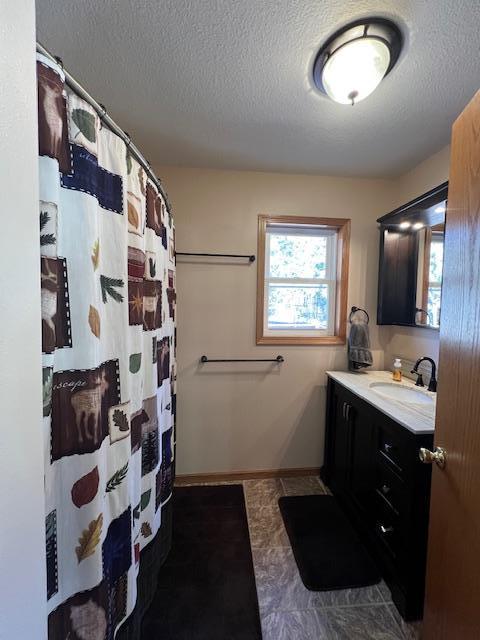 bathroom featuring baseboards, a shower with shower curtain, a textured ceiling, and vanity