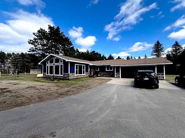 view of front of property featuring a garage, aphalt driveway, and stone siding